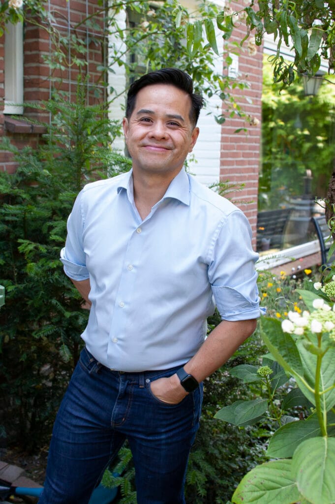 Hiep Truong in een voortuin, met op de achtergrond groen en een huis.